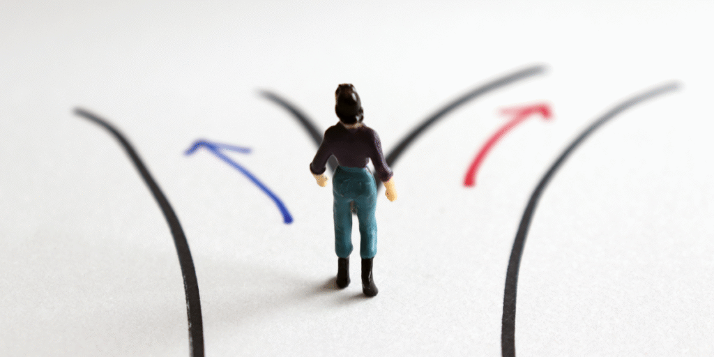 A miniature person stands on a path with arrows pointing in various directions, symbolizing diverse career paths in digital marketing.