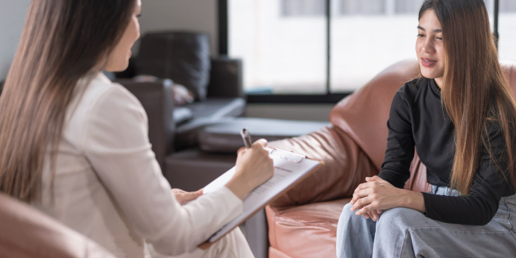 A woman sits on a couch, engaged in conversation with a therapist about career counseling options and guidance.